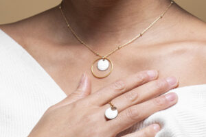 Vue rapprochée du pendentif anneau doré et émail blanc