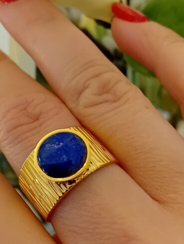 Bague en émail dorée portée sur une main